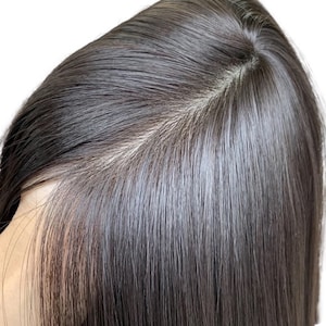 May include: Close-up of a person's dark brown hair, showing the texture and shine of the hair.