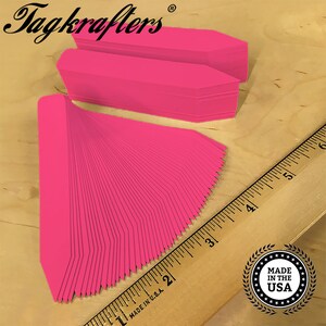 May include: A stack of 50 bright pink plant markers with pointed ends. The markers are made in the USA.  Tagkrafters is printed on the top of the stack.