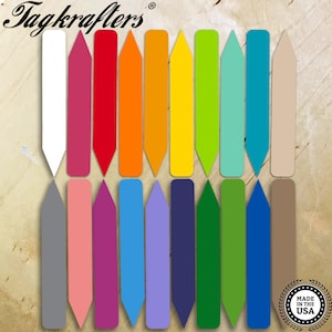 May include: Twenty-four plant markers in a variety of colors, including white, red, orange, yellow, green, blue, purple, and brown. The markers are made of plastic and have a pointed tip. The markers are arranged in two rows of twelve. The text "Tagkrafers®" is visible at the top of the image. The text "Made in the USA" is visible in a circle at the bottom of the image.