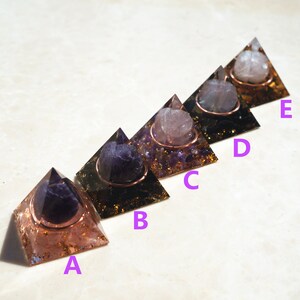May include: Five amethyst crystal pyramids with copper wire and gold flakes. Each pyramid has a different colored crystal sphere in the center. The pyramids are labeled A through E.