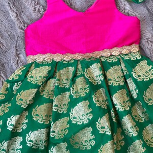 Puede incluir: Un vestido verde con un corpi&ntilde;o rosa y ribetes dorados. La falda tiene un patr&oacute;n de elefantes dorados sobre un fondo verde.