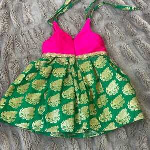 Puede incluir: Un vestido verde y rosa con escote halter y estampado de elefante. El vestido tiene un corpi&ntilde;o rosa y una falda verde con detalles dorados.