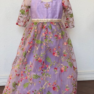 May include: A lavender dress with a floral embroidered tulle overlay. The dress has a satin bodice with a beaded neckline and a white satin belt.