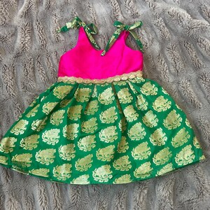 Puede incluir: Un vestido verde y rosa con ribete dorado y estampado de elefantes. El vestido tiene un corpi&ntilde;o sin mangas y una falda completa.
