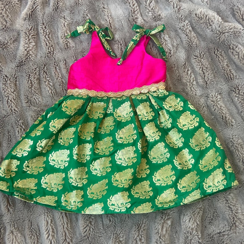 Puede incluir: Un vestido verde y rosa con ribete dorado y estampado de elefantes. El vestido tiene un corpi&ntilde;o sin mangas y una falda completa.