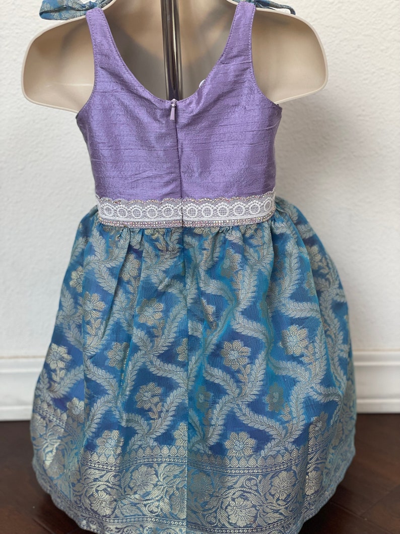 May include: A sleeveless dress with a lavender bodice and a blue and silver patterned skirt. The bodice has a white lace trim and a zipper in the back.