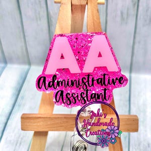 May include: Pink glitter badge reel with the letters "AA" and the text "Administrative Assistant".