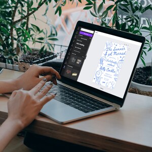 May include: A laptop computer displaying a digital design for a wedding invitation. The invitation is blue and white with hand-drawn illustrations of a beach scene and the text "The Summer I got Married".