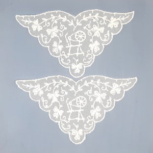 May include: Two white lace appliques shaped like butterfly wings. The lace is delicate and intricate, with a floral design.