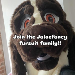 May include: A brown and white plush dog fursuit head featuring large orange eyes and black accents. The text "Join the Jaloefancy fursuit family!!" is overlaid in white letters across the center of the furry canine mask, which has a soft texture.