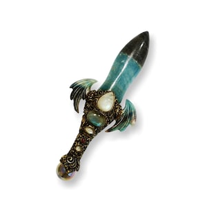May include: A decorative dagger with a blue and green gemstone blade, gold accents, and a crystal at the end of the handle.