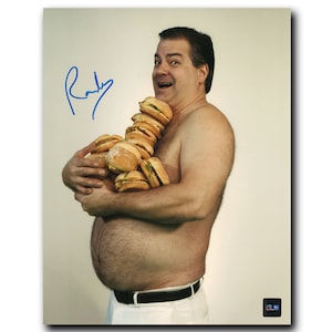 May include: A man with a bare chest holds a large stack of hamburgers in front of him. He is smiling and looking at the camera. The man is wearing white pants and a black belt. The image is signed "Randy".
