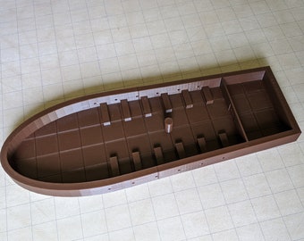 Könnte beinhalten: Ein braunes Plastikmodell eines Bootes mit einem rechteckigen Innenraum und einer geschwungenen Außenhülle. Das Modell hat eine Reihe kleiner rechteckiger Abteile an den Seiten.