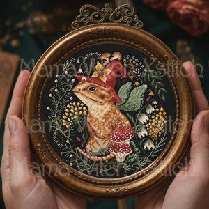 May include: A framed cross-stitch embroidery of a small animal wearing a red and yellow hat with mushrooms and flowers surrounding it.
