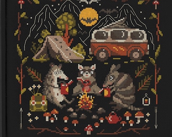 Op de afbeelding: Borduurpatroon met een busje, een tent, een kampvuur en drie dieren in een bosrijke omgeving. Het patroon is in een zwart frame met de tekst "Mama Witch Xstitch" en "Cross Stitch Patterns" onder het frame.