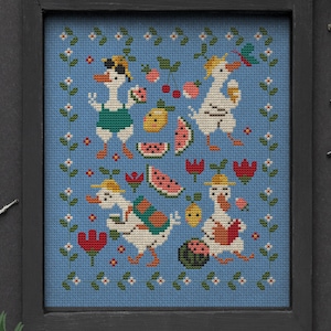 May include: Cross-stitch pattern featuring four ducks enjoying summer with watermelon, lemons, and cherries. The pattern is framed in a black frame and has a blue background with green vines and white flowers.