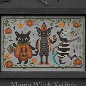May include: Cross stitch pattern featuring three black cats dressed up for Halloween. One cat is wearing a pumpkin costume, another is wearing a witch hat and holding a cup of coffee, and the third is wearing a striped costume and holding a candy bag. The pattern is set against a gray background with orange pumpkins and yellow flowers.