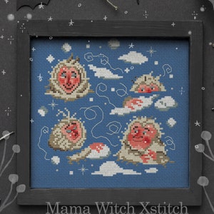 May include: Cross stitch pattern of four snow monkeys in a blue sky with white clouds. The monkeys are red and white and have a smiling expression. The pattern is framed in black.