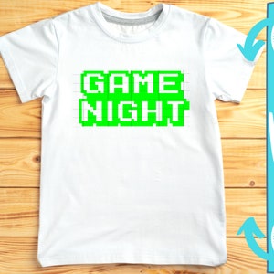 May include: A white t-shirt with a green pixelated design that says "GAME NIGHT".