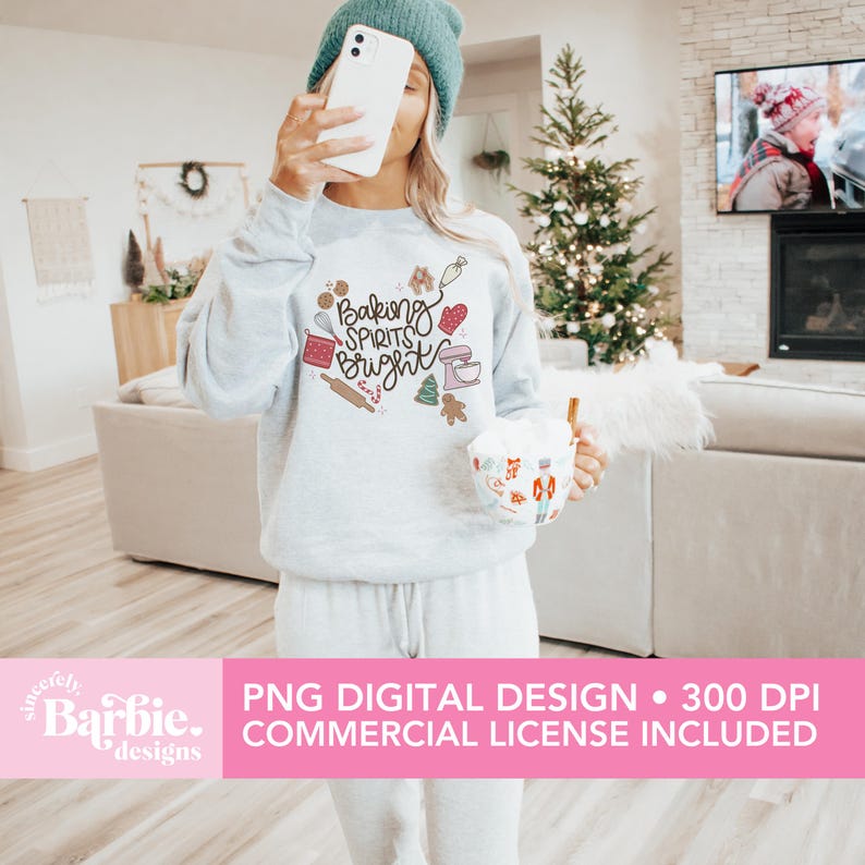 May include: A light gray sweatshirt with the text "Baking Spirits Bright" and baking-themed graphics. The design includes a rolling pin, mixer, gingerbread man, and other festive elements. The image also includes a teal beanie and a mug with a holiday design.