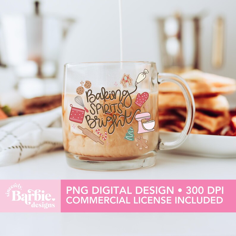 May include: A clear glass mug with the words "Baking Spirits Bright" and baking-themed illustrations. The mug contains a light brown liquid, possibly coffee or tea, and is being filled with a white liquid. The mug has a handle and is on a white surface.