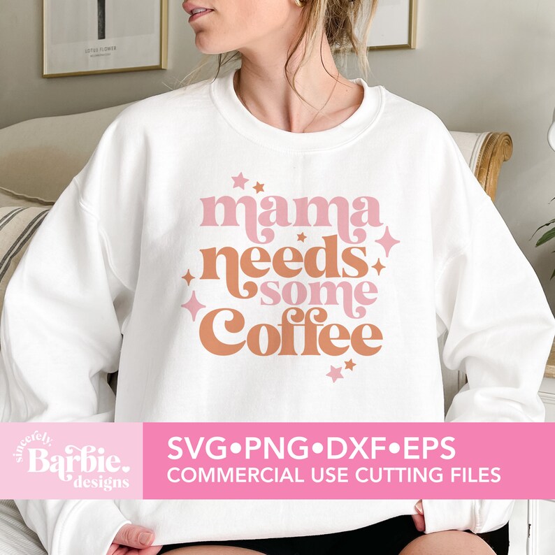Op de afbeelding: Wit sweatshirt met de tekst "mama needs some coffee" in roze en bruine letters met roze sterren. De tekst is in een retro-lettertype stijl.