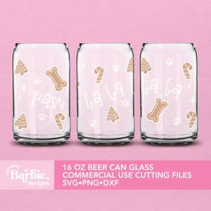 May include: Three clear 16 oz beer can glasses with festive designs. Each glass features tan-colored paw prints, bone, candy cane, and Christmas tree shapes. One glass has the word "paw", and the other two say "la la".