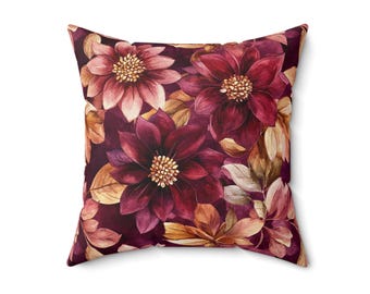 Cojín decorativo estampado a doble cara con diseño floral en tonos burdeos y rosa empolvado.