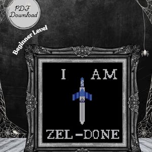 以下が含まれることがあります： 「I AM ZEL-DONE」の文字とピクセル化された剣のデザインが施された、黒いフレームのクロスステッチアート。「PDF Download」と「Beginner Level」の文字も表示されています。背景は暗く、クモの巣があります。
