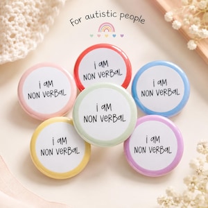 May include: A collection of six round, colorful pins with the text "i am NON VERBAL" in black. The pins have different colored borders: red, pink, blue, yellow, green, and purple. The phrase "For autistic people" is above the pins.