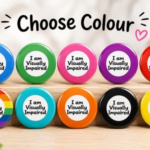 Puede incluir: Diez chapas redondas dispuestas en dos filas. Cada chapa presenta un círculo central blanco con el texto negro "I am Visually Impaired". Los anillos exteriores son azul, verde, rosa, morado, rojo, arcoíris, turquesa, naranja, negro y amarillo.