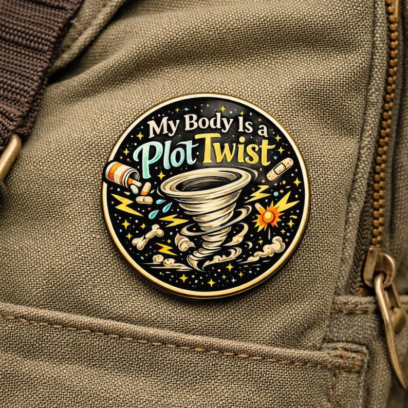 Puede incluir: Un pin esmaltado circular con fondo negro que presenta una ilustraci&oacute;n central de un tornado, rayos amarillos, un frasco de pastillas, una tirita y un hueso. El texto My Body Is a Plot Twist aparece en letras blancas y amarillas.