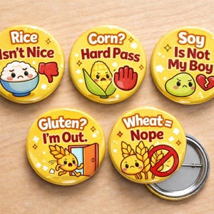 Puede incluir: Un conjunto de botones redondos amarillos con frases e ilustraciones relacionadas con la comida. Los botones incluyen textos como "Rice Isn't Nice", "Corn? Hard Pass" y "Soy Is Not My Boy". Cada botón tiene un diseño único.