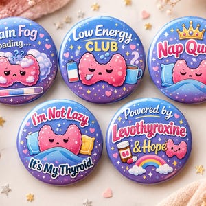 May include: Five circular pin-back buttons featuring purple backgrounds with stars and cartoon thyroid illustrations. Text includes Brain Fog Loading, Low Energy Club, Nap Queen, I'm Not Lazy It's My Thyroid, and Powered by Levothyroxine & Hope.