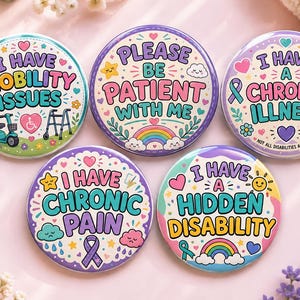 Könnte beinhalten: Fünf runde Ansteckbuttons mit farbenfrohen Illustrationen und Text. Die Buttons zeigen die Aufschriften I Have Mobility Issues, Please Be Patient With Me, I Have A Chronic Illness, I Have Chronic Pain und I Have A Hidden Disability.