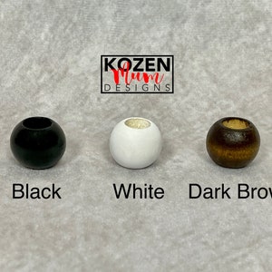 May include: Three wooden beads in black, white, and dark brown.  KOZEN Mum DESIGNS is printed above the beads.