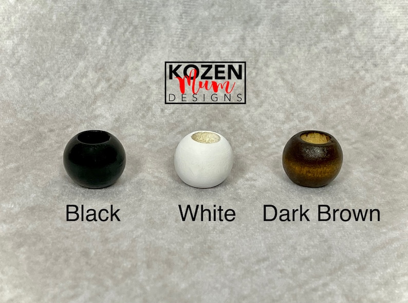 May include: Three wooden beads in black, white, and dark brown.  KOZEN Mum DESIGNS is printed above the beads.