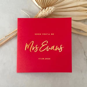 Tarjeta de boda con lámina dorada sobre una tarjeta gruesa ecológica de color rojo intenso. Tarjeta para el día de la boda para la novia, el novio, la esposa o el esposo.