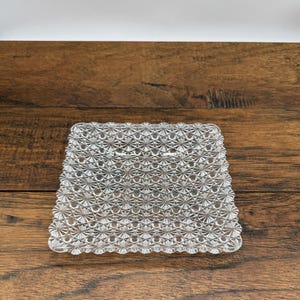 May include: A clear glass square serving tray with a raised, textured pattern.