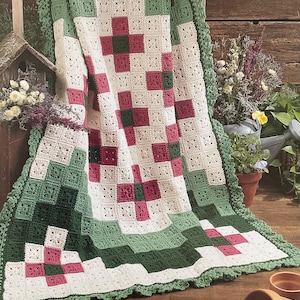 May include: A crocheted afghan blanket with a Bargello Garden design. The blanket features a pattern of squares in white, green, and burgundy. The edges are trimmed with a scalloped green border. The words "Bargello Garden" are printed at the bottom.
