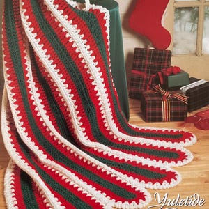 May include: A crocheted Christmas blanket in red, green, and white stripes. The blanket has a scalloped edge and is draped over a table. The words "Yuletide Delight" are visible in the lower right corner.