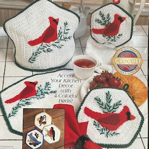 May include: A collection of white crochet kitchen accessories with a red cardinal bird design. The set includes a tea cozy, placemats, and pot holders. The text reads "Accent Your Kitchen Decor with 4 Colorful Birds!" and "Winning Crochet Designs."