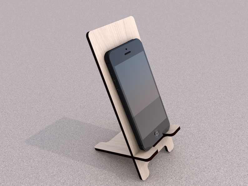May include: A wooden phone stand with a black smartphone resting on it. The stand is made of light wood and has a simple design.