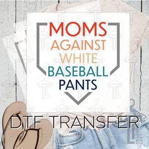 May include: A white iron-on transfer design with a baseball diamond shape and the text "MOMS AGAINST WHITE BASEBALL PANTS" in a colorful font.