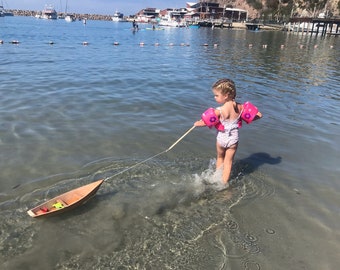 Houten speelgoedbootje met speelstokje en touwtje. Heldere afwerking binnen en buiten.