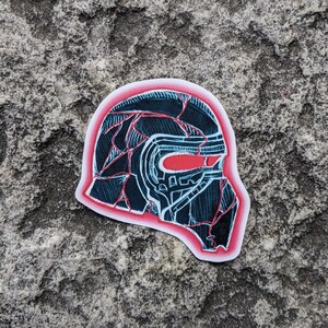 May include: A black and white illustration of a helmet with a red visor. The helmet is outlined in red and has a cracked, textured surface.