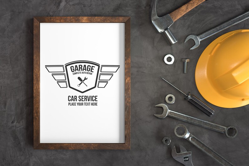 Puede incluir: Una impresi&oacute;n enmarcada con un logotipo en blanco y negro para un garaje. El logotipo presenta un escudo con las palabras "Garage Complete Auto Repair" y llaves inglesas cruzadas. Debajo del escudo hay alas y el texto "Car Service Place Your Text Here". La impresi&oacute;n est&aacute; rodeada de varias herramientas y un casco amarillo.