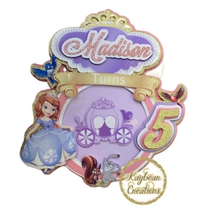 May include: Purple and gold glitter cake topper with a princess character, a carriage, and the words "Madison Turns 5".