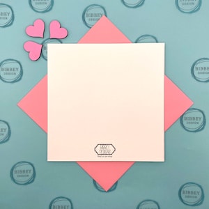 May include: A blank white card with a pink border is on a blue background with a repeating pattern of pink circles with the text "Bibbey Design". The card has a small black and white logo that says "Bibbey Designs" and "Find us on Etsy".