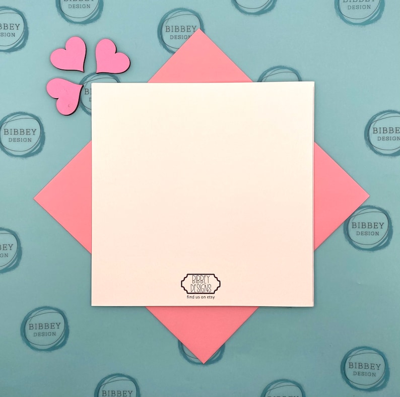 May include: A blank white card with a pink border is on a blue background with a repeating pattern of pink circles with the text "Bibbey Design". The card has a small black and white logo that says "Bibbey Designs" and "Find us on Etsy".